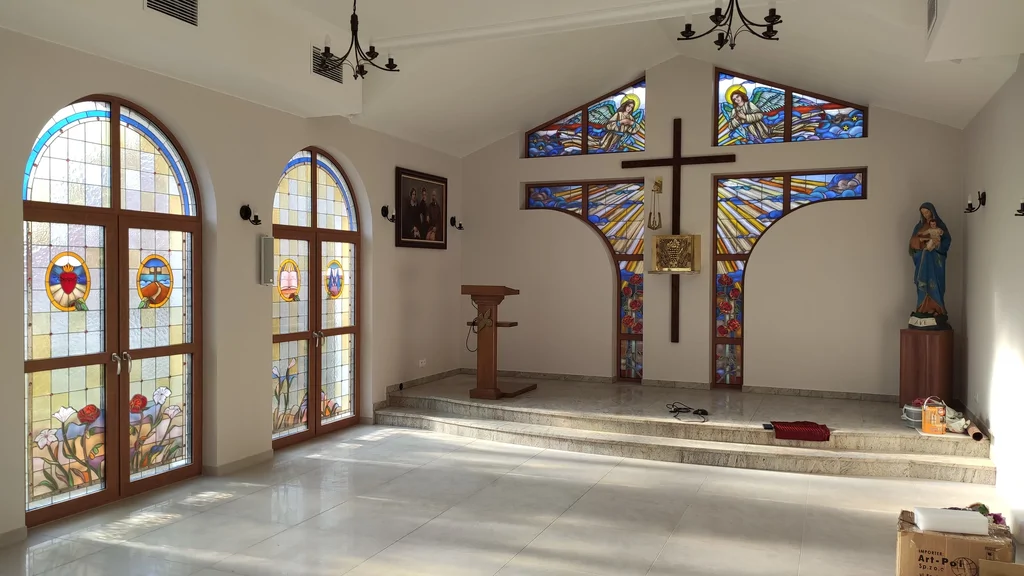 Wnętrze kaplicy w domu zakonnym w Ostródzie, z witrażami, krzyżem i podwyższonym prezbiterium