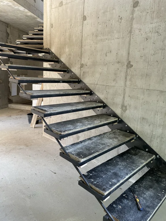 Tymczasowe schody stalowe zamontowane we wnętrzu domu jednorodzinnego o konstrukcji żelbetowej