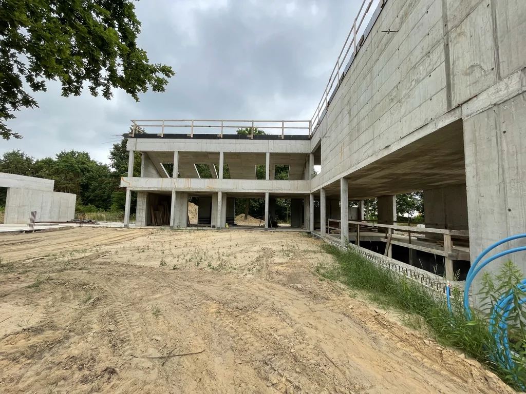 Widok dziedzińca: żelbetowe słupy i stropy oraz ściany z betonu architektonicznego – stan surowy.