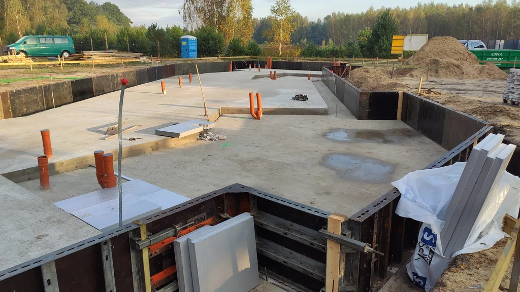 Płyta fundamentowa przed betonowaniem – widoczne uskoki poziomów i przejścia instalacyjne na powierzchni.