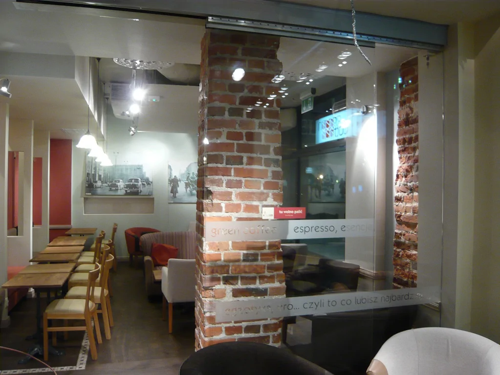 Gotowe wnętrze Green Caffè Nero z przeszkloną ścianką, ceglanymi filarami i stolikami