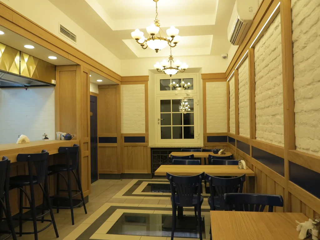 zdjęcie piekarni wewnątrz, stoliki, posadzka z podświetlanymi otworami, na ścianach kamień i drewno 