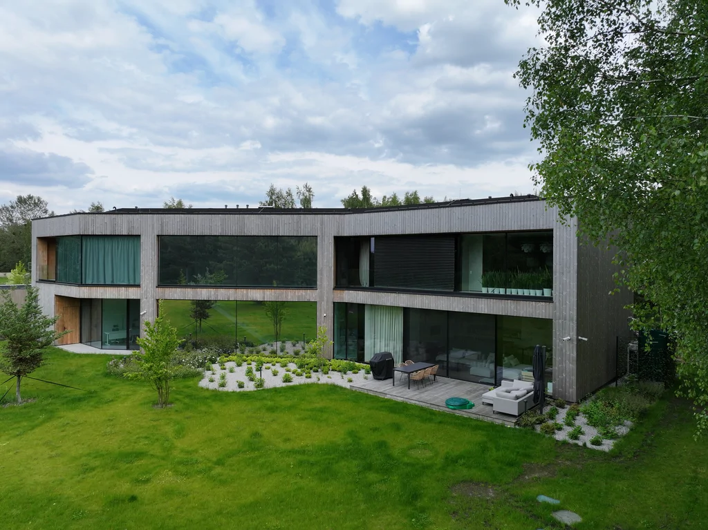 Dom Prawdziwka – elewacja ogrodowa z tarasem i przeszkleniami na dwie kondygnacje, ujęcie z drona.