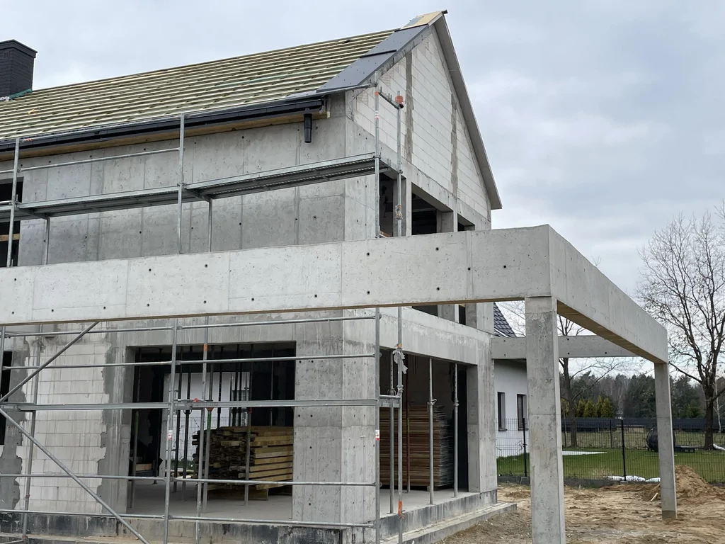Żelbetowa konstrukcja budynku z wykonanym zadaszeniem tarasu oraz otwartą strefą parteru w trakcie realizacji