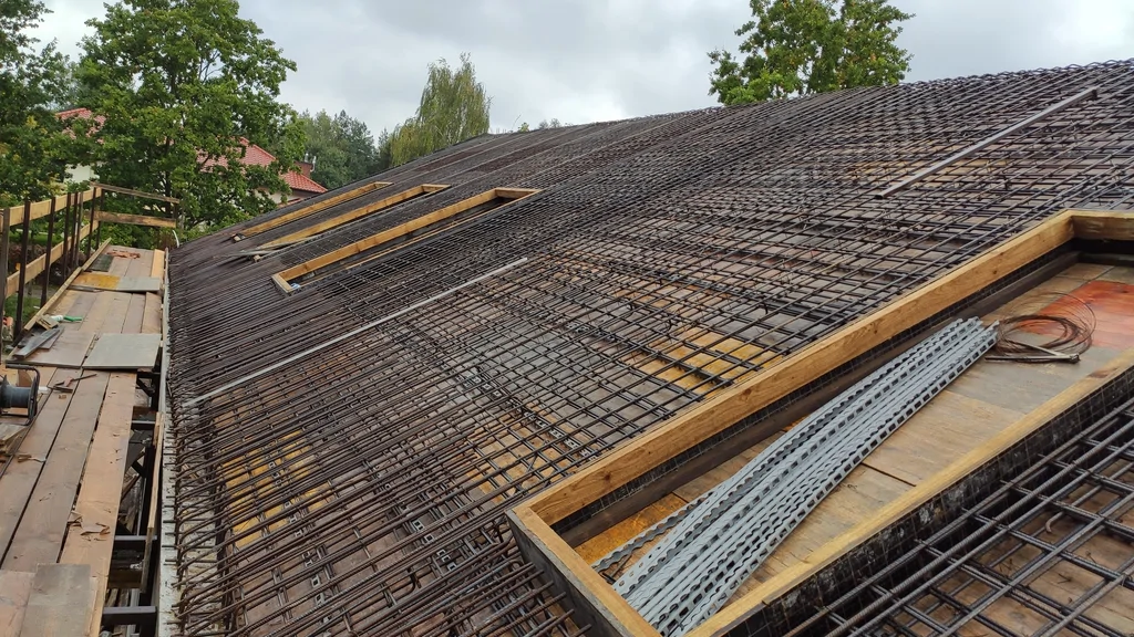 Skośny strop żelbetowy ze zbrojeniem i otworami pod świetliki – przygotowanie do wylania betonu