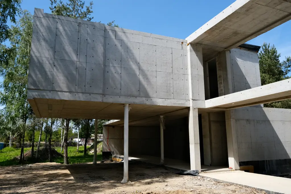 Żelbetowa konstrukcja nowoczesnego domu w trakcie budowy widziana od strony ogrodu.