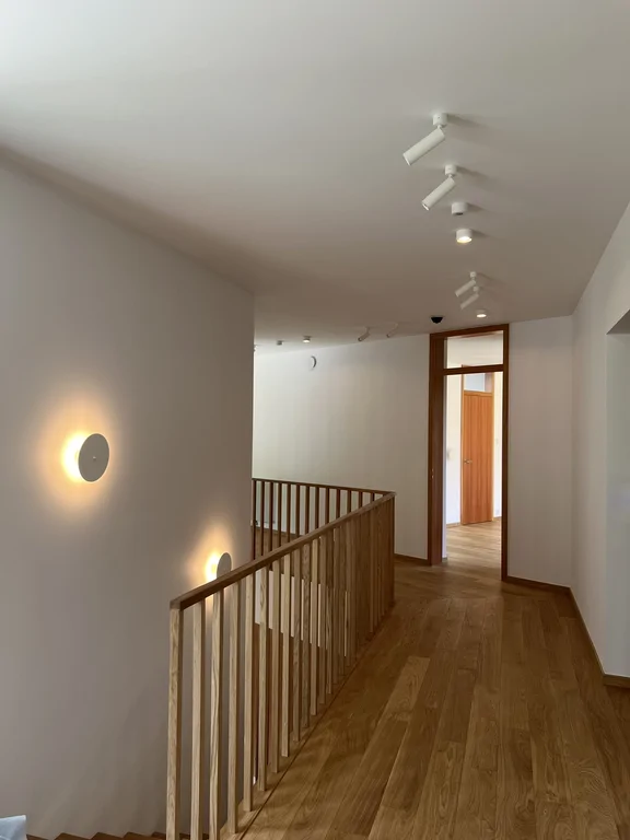 Korytarz na piętrze z drewnianą balustradą i oświetleniem sufitowym