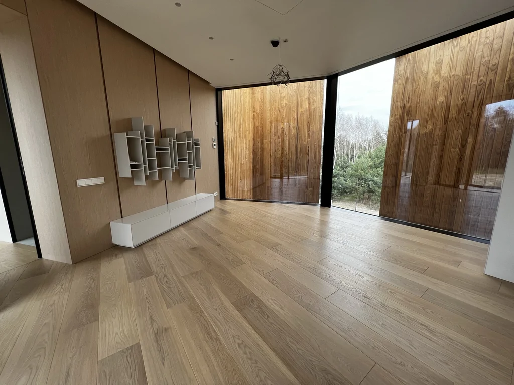 Drewniana okładzina ścienna z niską szafką oraz modułową kompozycją półek. Kontrast ciepłego drewna i jasnych frontów.