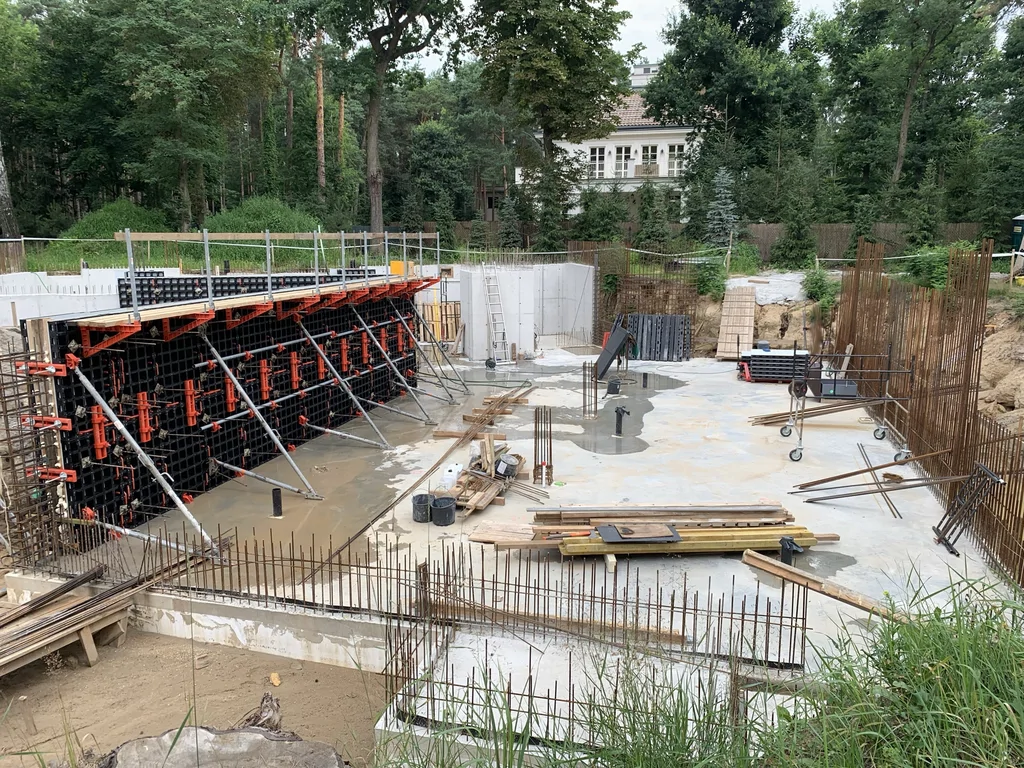 Widok wnętrza szczelnej piwnicy domu jednorodzinnego z płytą fundamentową, zbrojeniem i systemowymi szalunkami ścian