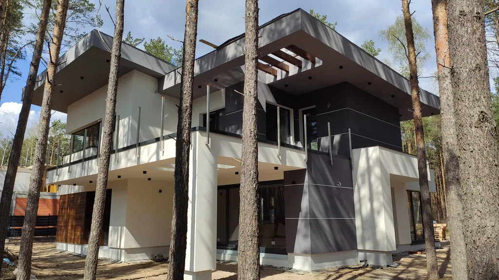 Nowoczesny dom po wykonaniu elewacji w bieli i graficie, płaskie dachy z dużymi okapami