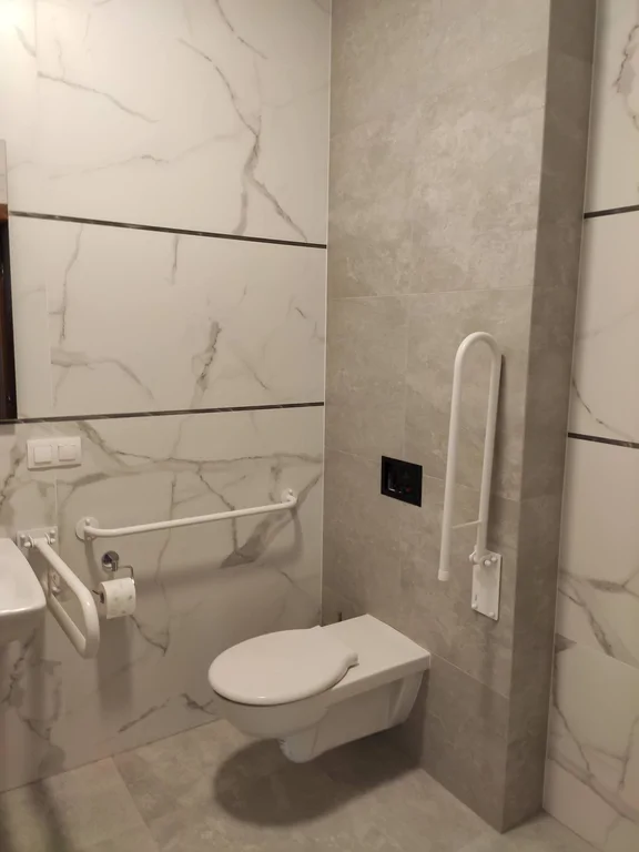 łazienka przystosowana dla osób niepełnosprawnych, płytki na podłodze i ścianie 