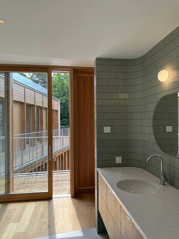 Łazienka z lustrzaną zabudową, zieloną okładziną ścienną i widokiem na balkon