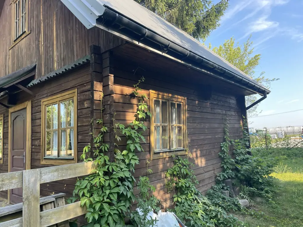 Zbliżenie frontowej elewacji drewnianego domku przed odnowieniem.