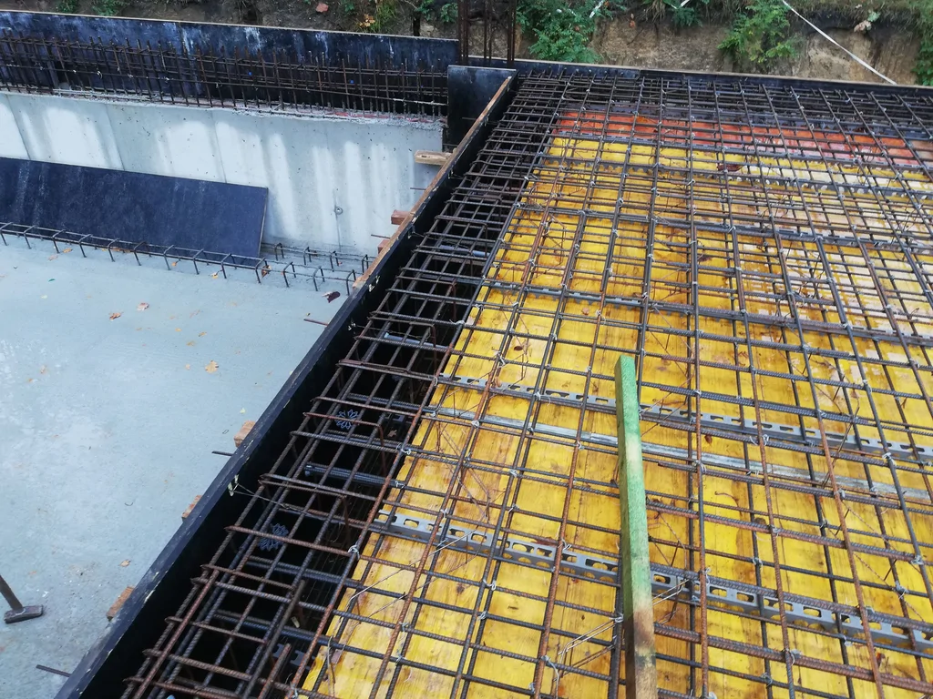 Krawędź stropu nad piwnicą z widocznym zbrojeniem oraz połączeniem ze ścianą żelbetową