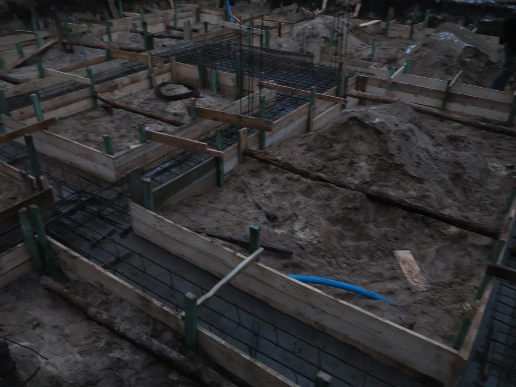 Budowa domu jednorodzinnego, widoczne zbrojenie i szalunek ław fundamentowych