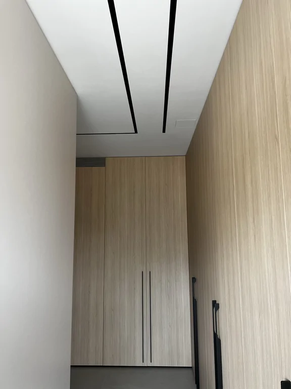 Szafy od podłogi do sufitu z długimi, czarnymi uchwytami. Minimalistyczny układ i czyste podziały.