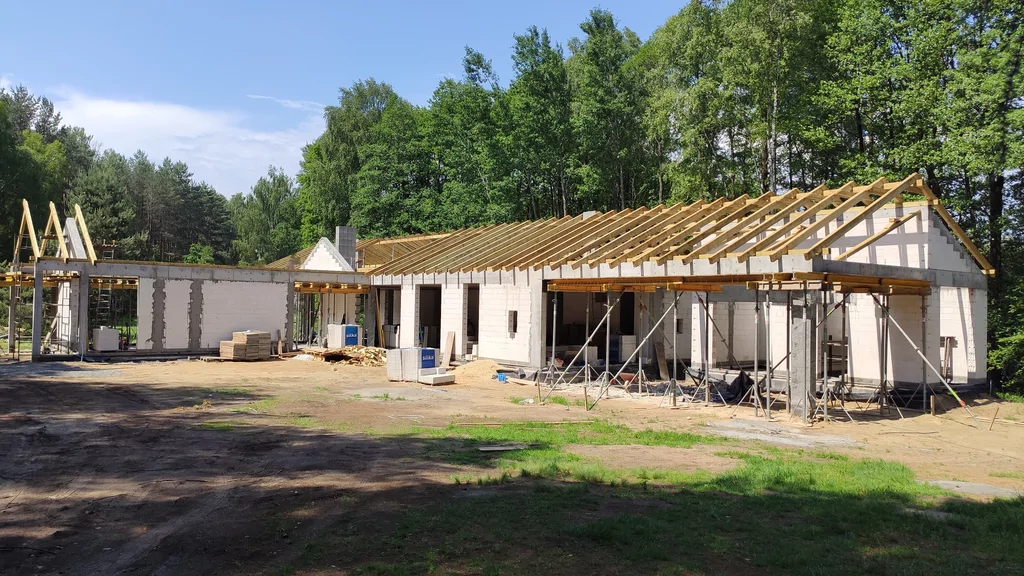 Montaż konstrukcji więźby dachu dwuspadowego – budynek parterowy w trakcie prac ciesielskich