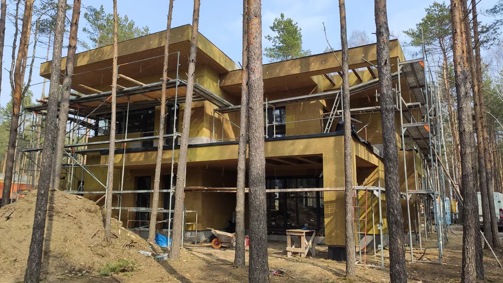 Ocieplanie elewacji: budynek w rusztowaniach z warstwą izolacji, trwające prace zewnętrzne