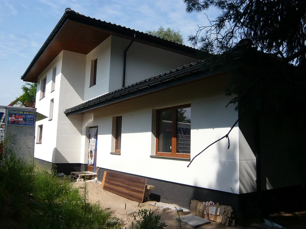 Zewnętrzny widok budynku po wykonaniu elewacji – okna w brązowej stolarce i rynny