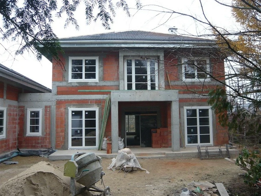 elewacja z balkonem nad wejściem, zamontowana stolarka okienna, prace na podwórzu