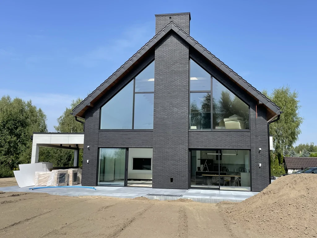 Front domu – przeszklenia w szczycie, centralny komin, taras na parterze